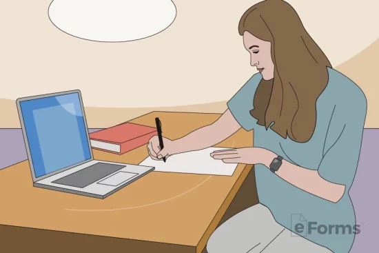 Woman writing a paper with pen alongside a laptop computer